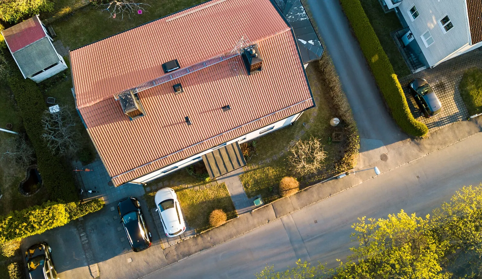Vista aerea di una casa con il tetto in tegole rosse lungo una strada residenziale