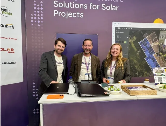 Drei Eturnity-Mitarbeitende hinter der Theke am Messestand, dahinter die Partnerlogos und die Planungssoftware