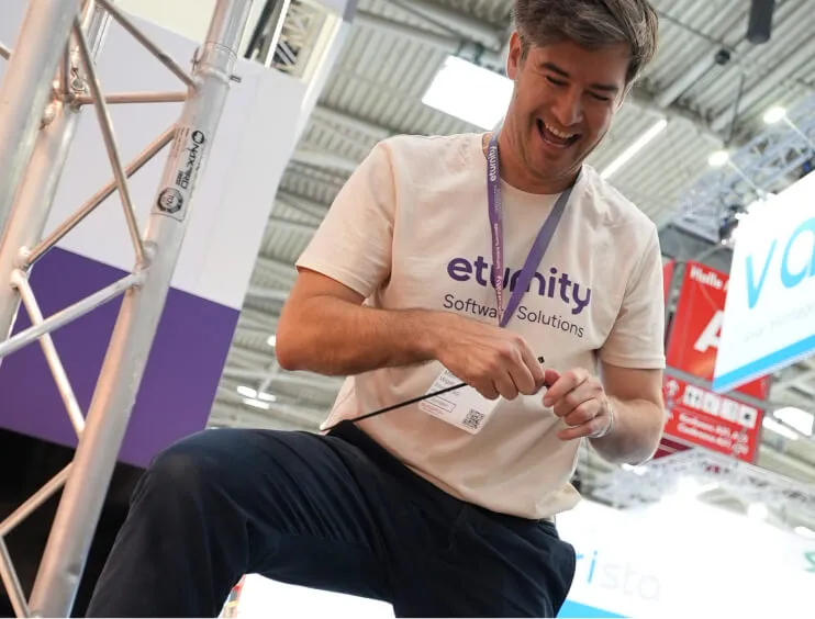 Ein lachender Eturnity-Mitarbeiter beim Aufbau des Messestands