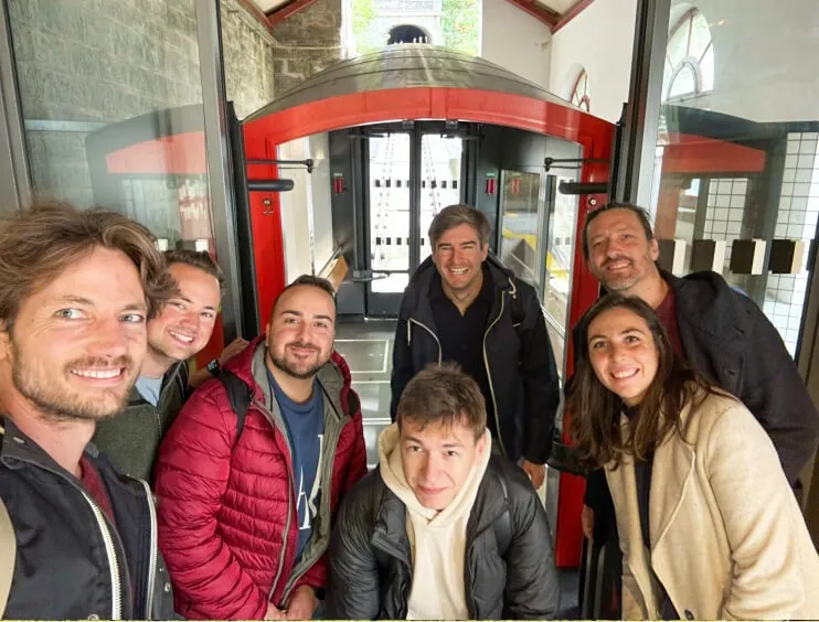 Sieben Mitglieder des Eturnity-Teams machen ein Selfie vor einer roten Standseilbahn