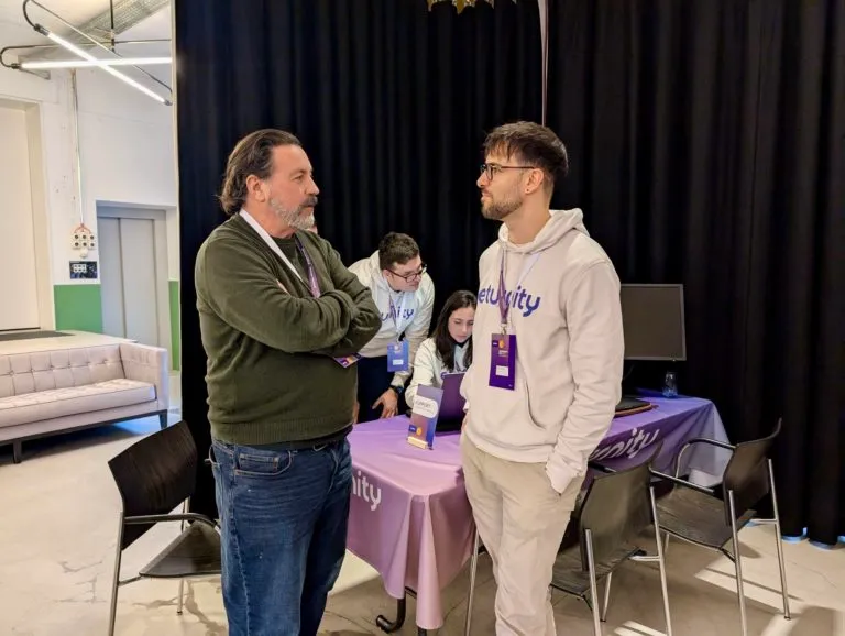 Eturnity-Mitarbeitende in Hoodies im Gespräch mit einem Besucher am Stand