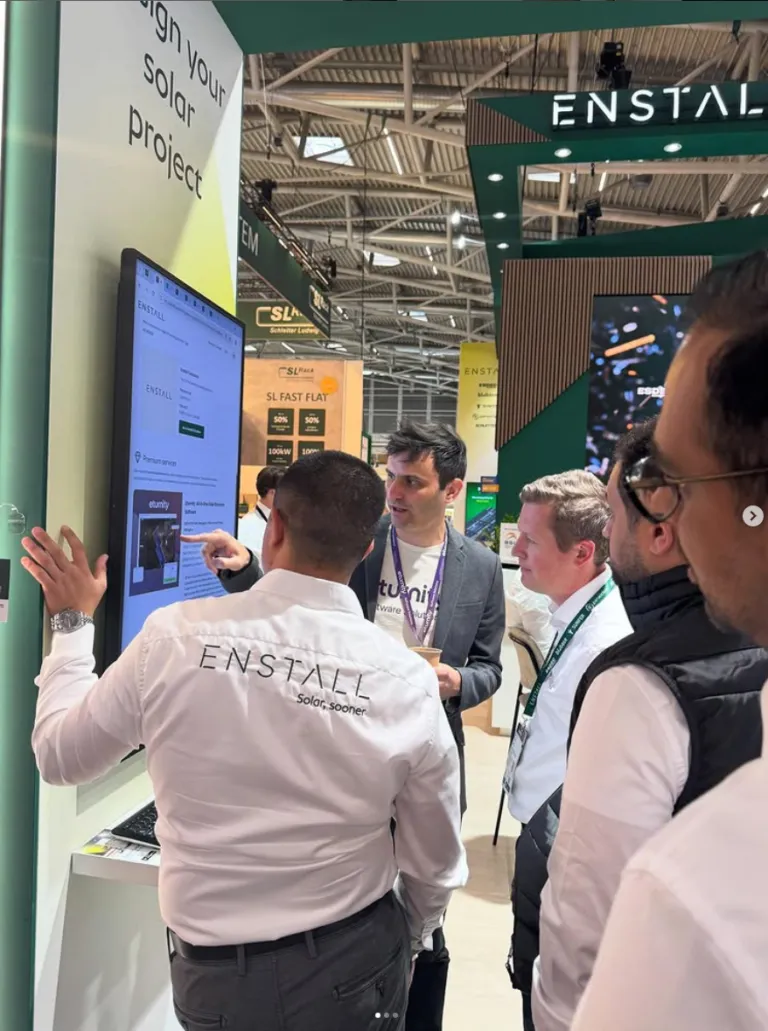 Besucher verfolgen eine Software-Demo auf dem Touchscreen am Messestand