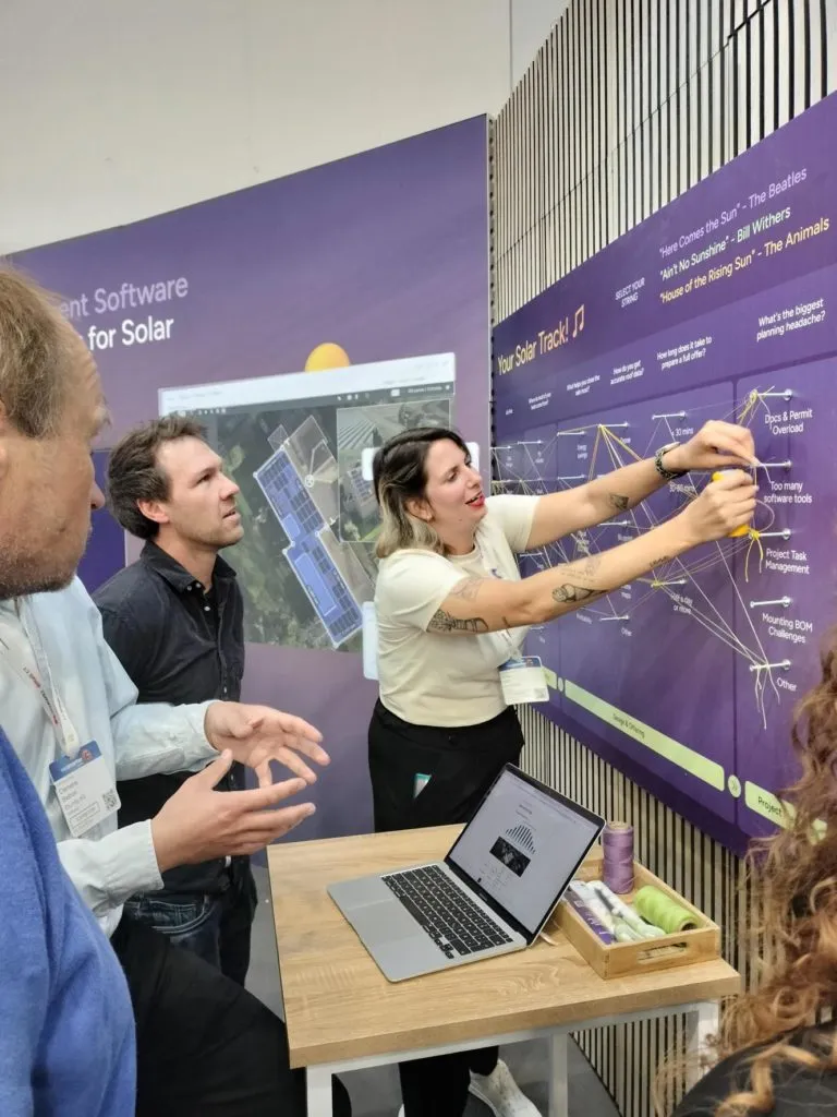 Ein Eturnity-Mitarbeiter zeigt zwei Besuchern die Solar Journey Map am Stand