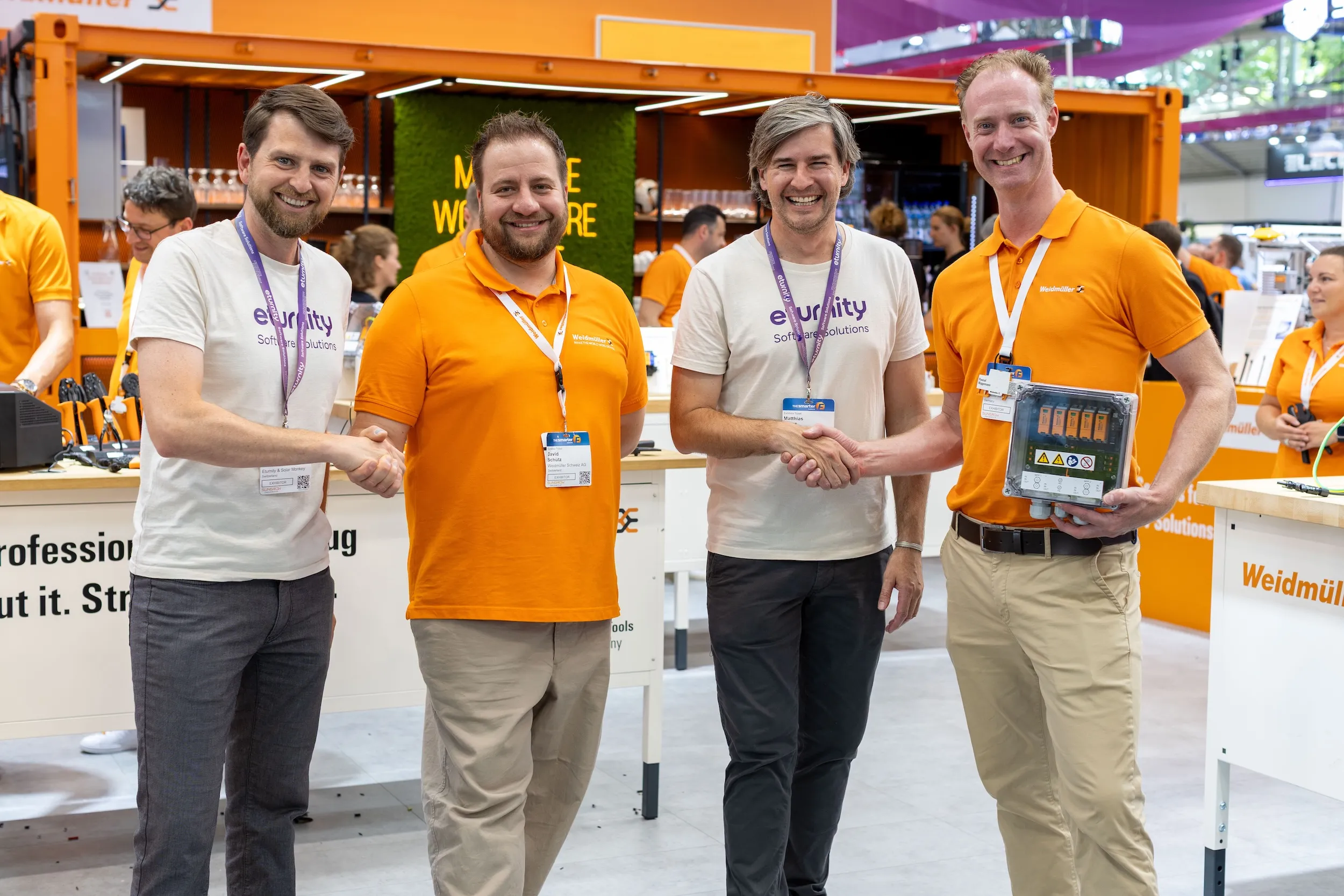 Zwei Mitarbeitende von Eturnity und zwei von Weidmüller geben sich am Messestand die Hand