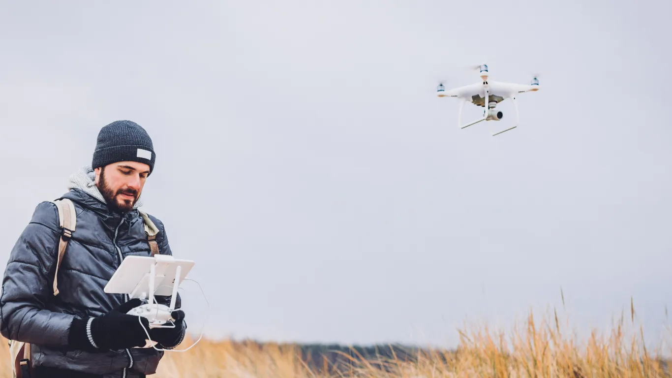 A man in a field flying a drone with a remote control